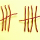 Dünne Würstchen als angeordnet als Nummer 5 in Strichzählung auf gelbem Hintergrund