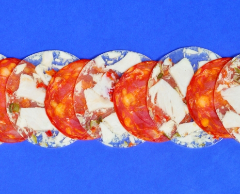 Salami und Sülze in dünnen Scheiben aufgereit auf blauem Untergrund
