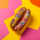 A Pair of sausages placed on yellow, pink and orange background